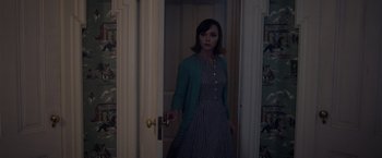 Movie still from “Monstrous” (2022), directed by Chris Sivertson – A woman standing in front of a door in a room; Medium shot, High angle
