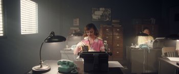 Movie still from “Monstrous” (2022), directed by Chris Sivertson – A woman sitting in front of an old fashioned typewriter; Medium shot, Low angle