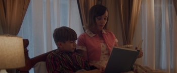 Movie still from “Monstrous” (2022), directed by Chris Sivertson – A woman sitting next to a young boy on a laptop computer; Medium shot, High angle
