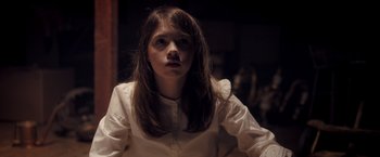 Movie still from “Monstrous” (2022), directed by Chris Sivertson – A woman in a white shirt is looking at the camera; Close Up shot, High angle