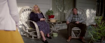 Movie still from “Monstrous” (2022), directed by Chris Sivertson – A woman and a man sitting in rocking chairs on a porch; Wide shot, Low angle