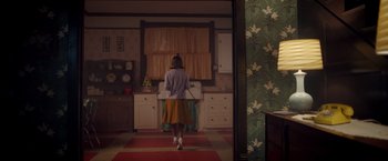 Movie still from “Monstrous” (2022), directed by Chris Sivertson – A woman standing in front of a sink in a kitchen; Wide shot, High angle
