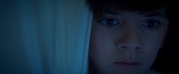 Movie still from “Monstrous” (2022), directed by Chris Sivertson – A person's face in a dark room; Extreme Close Up shot, Low angle