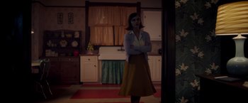 Movie still from “Monstrous” (2022), directed by Chris Sivertson – A woman standing in a kitchen with her arms crossed; Medium shot, Low angle