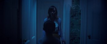 Movie still from “Monstrous” (2022), directed by Chris Sivertson – A man and a woman are standing in a doorway; Medium shot, Over the shoulder angle