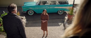 Movie still from “Monstrous” (2022), directed by Chris Sivertson – A woman standing in front of an old blue car; Wide shot, High angle