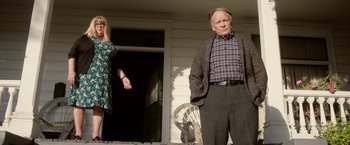 Movie still from “Monstrous” (2022), directed by Chris Sivertson – An older man and a younger woman standing on a porch; Medium shot, Low angle