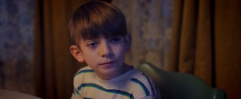 Movie still from “Monstrous” (2022), directed by Chris Sivertson – A young boy sitting in front of a window; Close Up shot, High angle