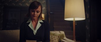 Movie still from “Monstrous” (2022), directed by Chris Sivertson – A woman is reading a book in a dark room; Medium shot, Low angle