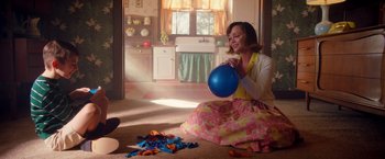 Movie still from “Monstrous” (2022), directed by Chris Sivertson – A woman sitting on the floor holding a blue balloon; Medium shot, High angle
