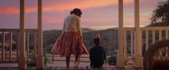 Movie still from “Monstrous” (2022), directed by Chris Sivertson – A woman and a child standing on a porch; Wide shot, Over the shoulder angle