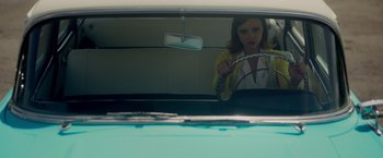 Movie still from “Monstrous” (2022), directed by Chris Sivertson – A woman in a car looking in the mirror; Medium shot, Low angle