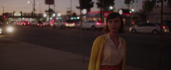 Movie still from “Monstrous” (2022), directed by Chris Sivertson – A woman standing on the side of a road at night; Medium shot, Over the shoulder angle
