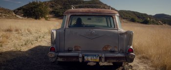 Movie still from “Monstrous” (2022), directed by Chris Sivertson – An old car is driving down a dirt road; Wide shot, Low angle