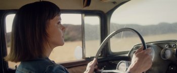 Movie still from “Monstrous” (2022), directed by Chris Sivertson – A woman sitting in the driver's seat of a truck; Close Up shot, High angle