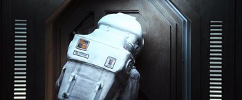 Movie still from “Moon” (2009), directed by Duncan Jones – An astronaut suit is shown on the stairs; Medium shot, Overhead angle