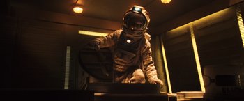 Movie still from “Moon” (2009), directed by Duncan Jones – A person in a spacesuit is standing on a platform; Medium shot, Low angle