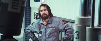 Movie still from “Moon” (2009), directed by Duncan Jones – A man with a beard and a jacket on; Medium shot, Low angle
