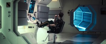 Movie still from “Moon” (2009), directed by Duncan Jones – A man sitting in a chair in front of a computer screen; Wide shot, High angle