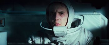 Movie still from “Moon” (2009), directed by Duncan Jones – A man in a spacesuit is looking at the camera; Close Up shot, Low angle