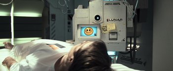 Movie still from “Moon” (2009), directed by Duncan Jones – A person sleeping on a bed in front of a computer screen; Close Up shot, Overhead angle