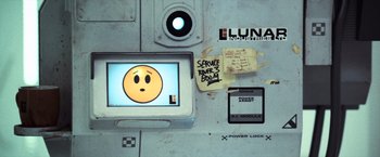 Movie still from “Moon” (2009), directed by Duncan Jones – A computer monitor with a smiley face on it; Close Up shot, Overhead angle