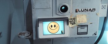 Movie still from “Moon” (2009), directed by Duncan Jones – A computer screen with a smiley face on it; Extreme Close Up shot, Overhead angle