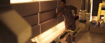 Movie still from “Moon” (2009), directed by Duncan Jones – A man standing next to a wall in a room; Medium shot, Overhead angle