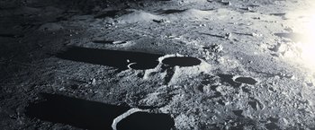 Movie still from “Moon” (2009), directed by Duncan Jones – A black and white photo of a crater on the surface of the moon; Extreme Wide shot, Overhead angle