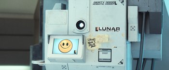 Movie still from “Moon” (2009), directed by Duncan Jones – A computer screen with a smiley face on it; Extreme Close Up shot, Overhead angle