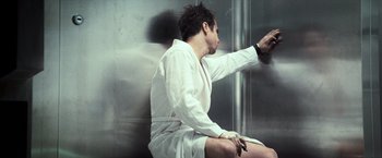 A man in a robe sitting on a chair in front of a mirror