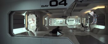 Movie still from “Moon” (2009), directed by Duncan Jones – A man sitting on the ground in a room; Extreme Wide shot, Overhead angle