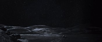 Movie still from “Moon” (2009), directed by Duncan Jones – A person standing on a hill at night; Extreme Wide shot, High angle