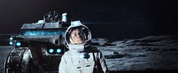 Movie still from “Moon” (2009), directed by Duncan Jones – A man in a spacesuit standing next to a space ship; Wide shot, Low angle