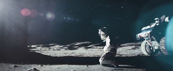 Movie still from “Moon” (2009), directed by Duncan Jones – An astronaut kneeling on the moon at night; Extreme Wide shot, Overhead angle