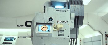 Movie still from “Moon” (2009), directed by Duncan Jones – An old video camera with a smiley face on the screen; Close Up shot, Overhead angle