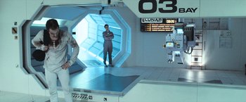 Movie still from “Moon” (2009), directed by Duncan Jones – A man standing inside of a room with a robot; Wide shot, Over the shoulder angle
