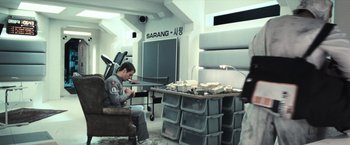 Movie still from “Moon” (2009), directed by Duncan Jones – A man sitting on a chair in a room; Wide shot, High angle