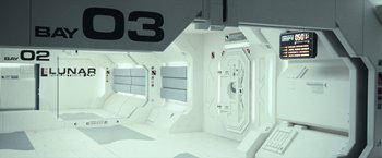 Movie still from “Moon” (2009), directed by Duncan Jones – A white room with a number on the wall and windows; Extreme Wide shot, Overhead angle