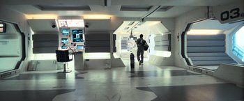 Movie still from “Moon” (2009), directed by Duncan Jones – A man walking through a hallway in a building; Wide shot, High angle