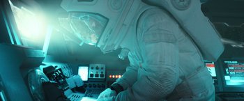 Movie still from “Moon” (2009), directed by Duncan Jones – A person in a spacesuit working on a computer; Medium shot, Overhead angle