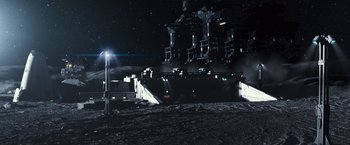 Movie still from “Moon” (2009), directed by Duncan Jones – A train station with a train on it's tracks at night; Extreme Wide shot, High angle