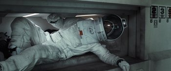 Movie still from “Moon” (2009), directed by Duncan Jones – A person in a spacesuit laying on the ground; Medium shot, Overhead angle