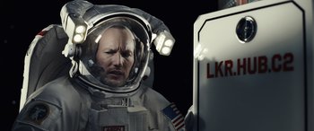 Movie still from “Moonfall” (2022), directed by Roland Emmerich – A man in a spacesuit is standing in front of a sign; Close Up shot, Low angle