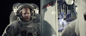 Movie still from “Moonfall” (2022), directed by Roland Emmerich – A man in a spacesuit is reflected in a mirror; Medium shot, Overhead angle