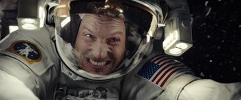 Movie still from “Moonfall” (2022), directed by Roland Emmerich – A man in a spacesuit is smiling for the camera; Close Up shot, Overhead angle