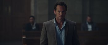 Movie still from “Moonfall” (2022), directed by Roland Emmerich – A man in a suit and tie standing in front of a group of people; Close Up shot, Low angle