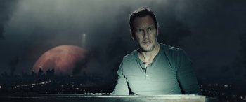 Movie still from “Moonfall” (2022), directed by Roland Emmerich – A man sitting in front of a body of water at night; Close Up shot, Over the shoulder angle