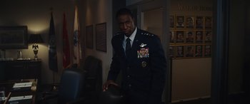 Movie still from “Moonfall” (2022), directed by Roland Emmerich – A man in a military uniform is holding a hat; Medium shot, Over the shoulder angle