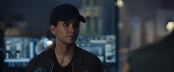 Movie still from “Moonfall” (2022), directed by Roland Emmerich – A woman wearing a baseball cap and a jacket; Close Up shot, Over the shoulder angle